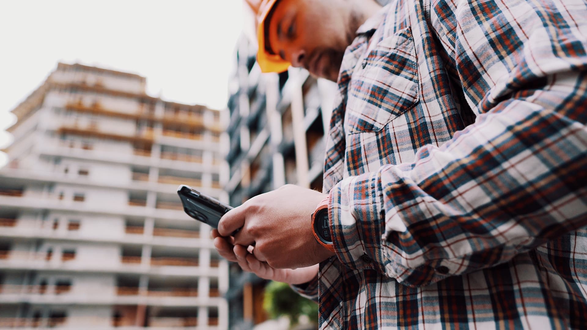 A commercial contractor uses his phone at a job site for marketing and communication