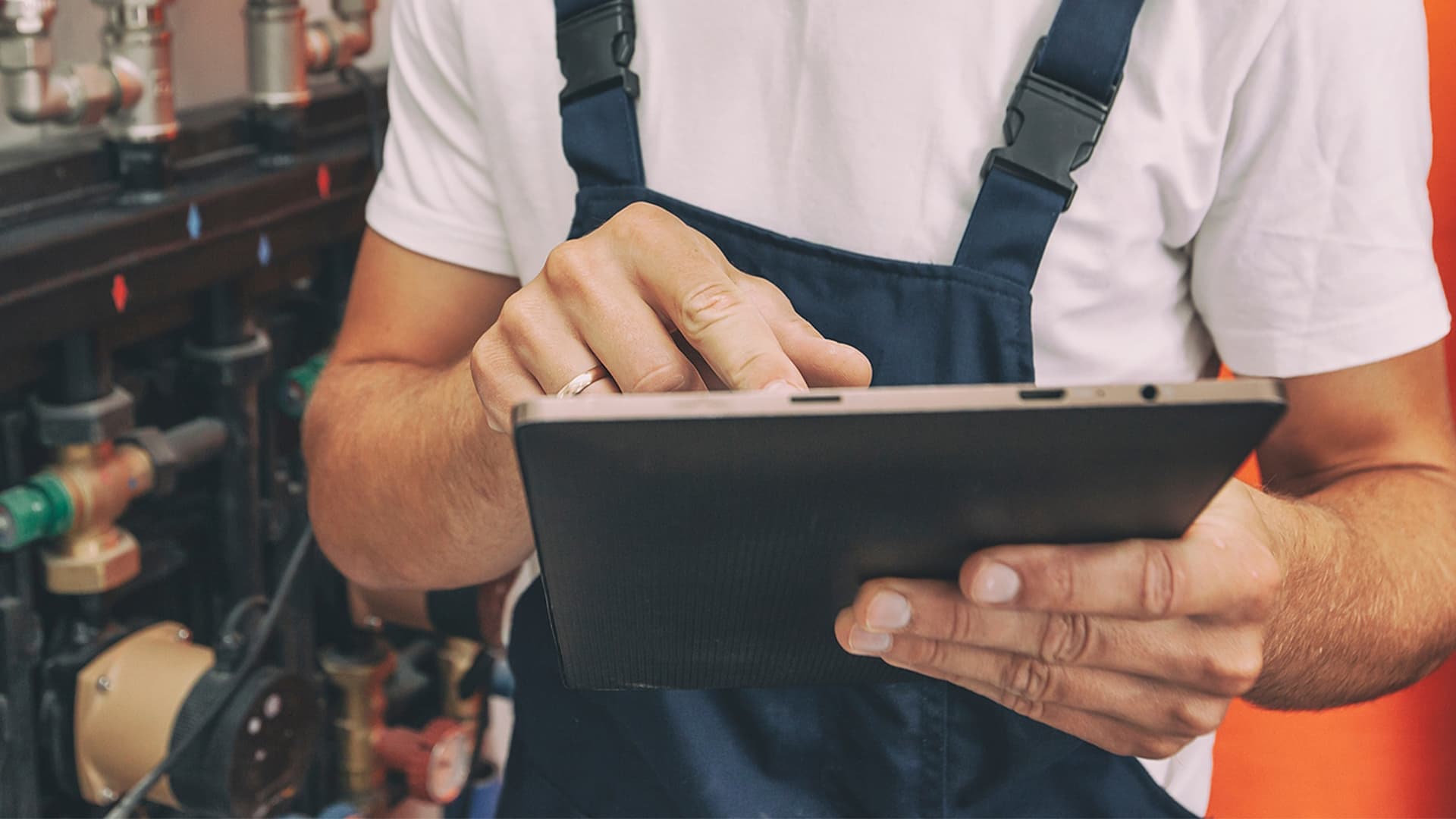 A commercial plumbing technician uses a tablet