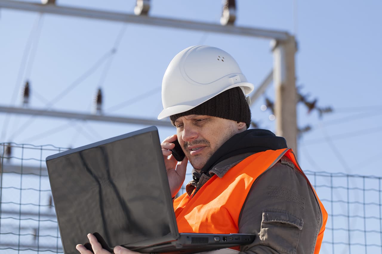 A solar project coordinator checks a laptop at a commercial jobsite