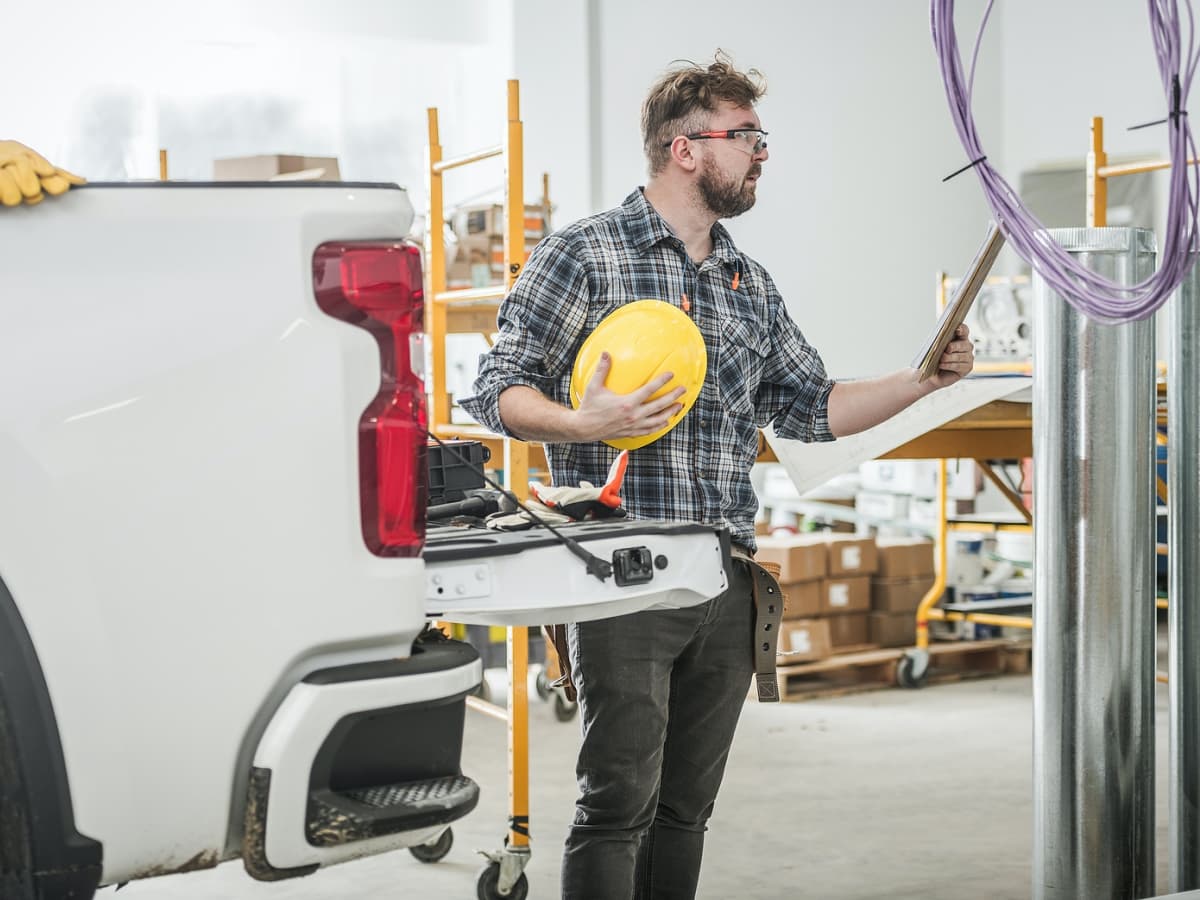 Construction worker in hard hat and helmet by truck.