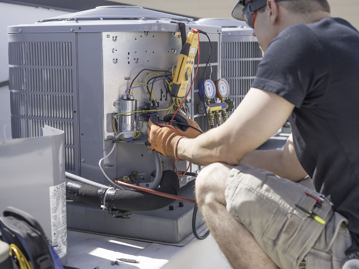 An HVAC contractor who uses real-time software to manage multiple jobsites works on an HVAC system.