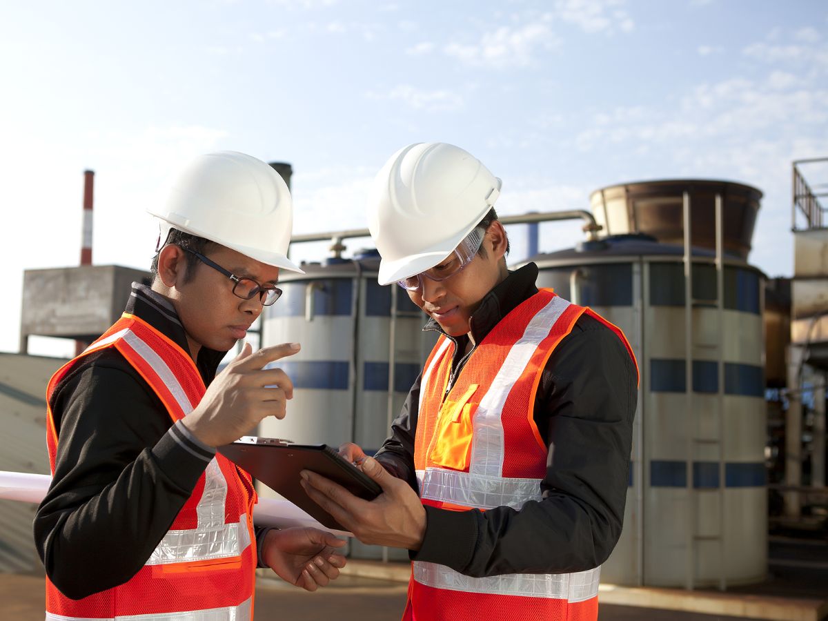 Two construction workers in hard hats and high visibility vests on a job site