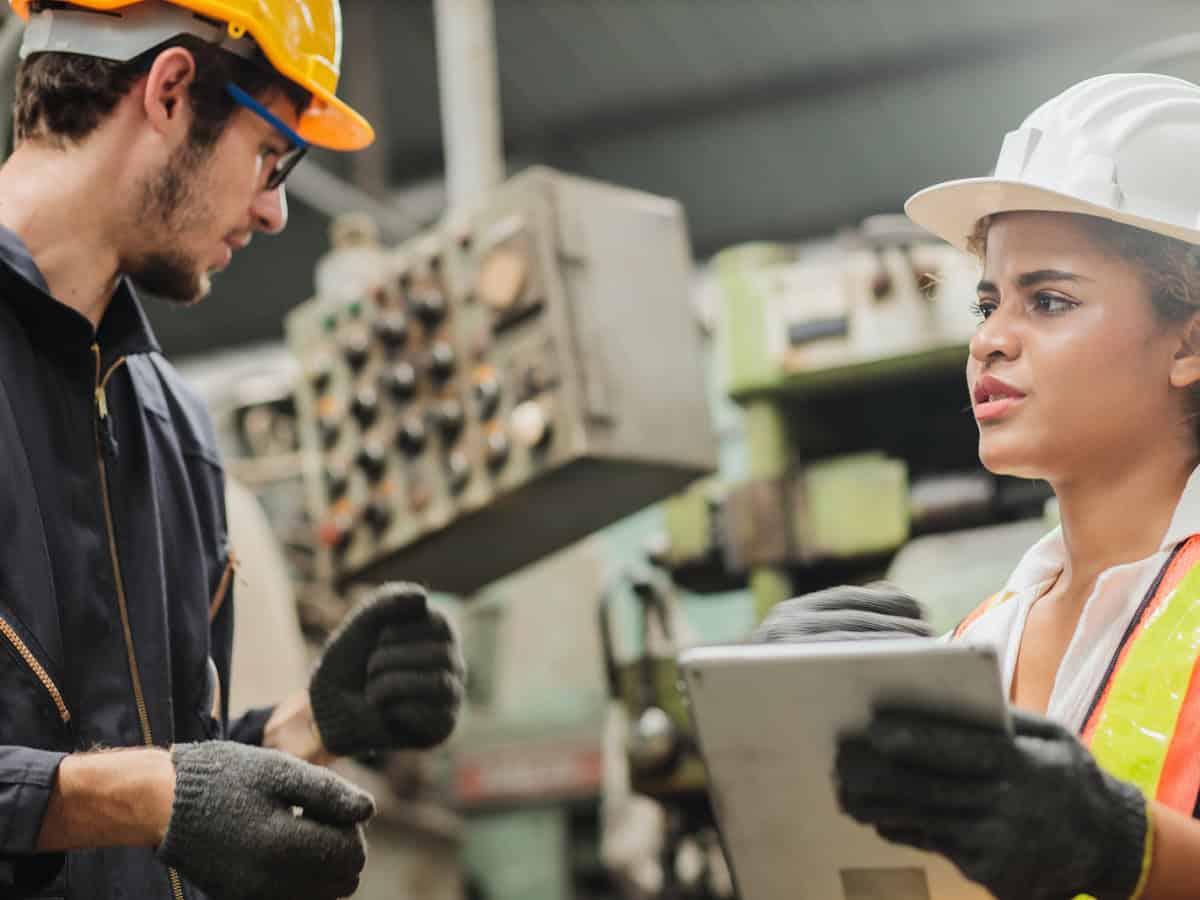 Woman in hard hat holds clipboard, looks frustrated