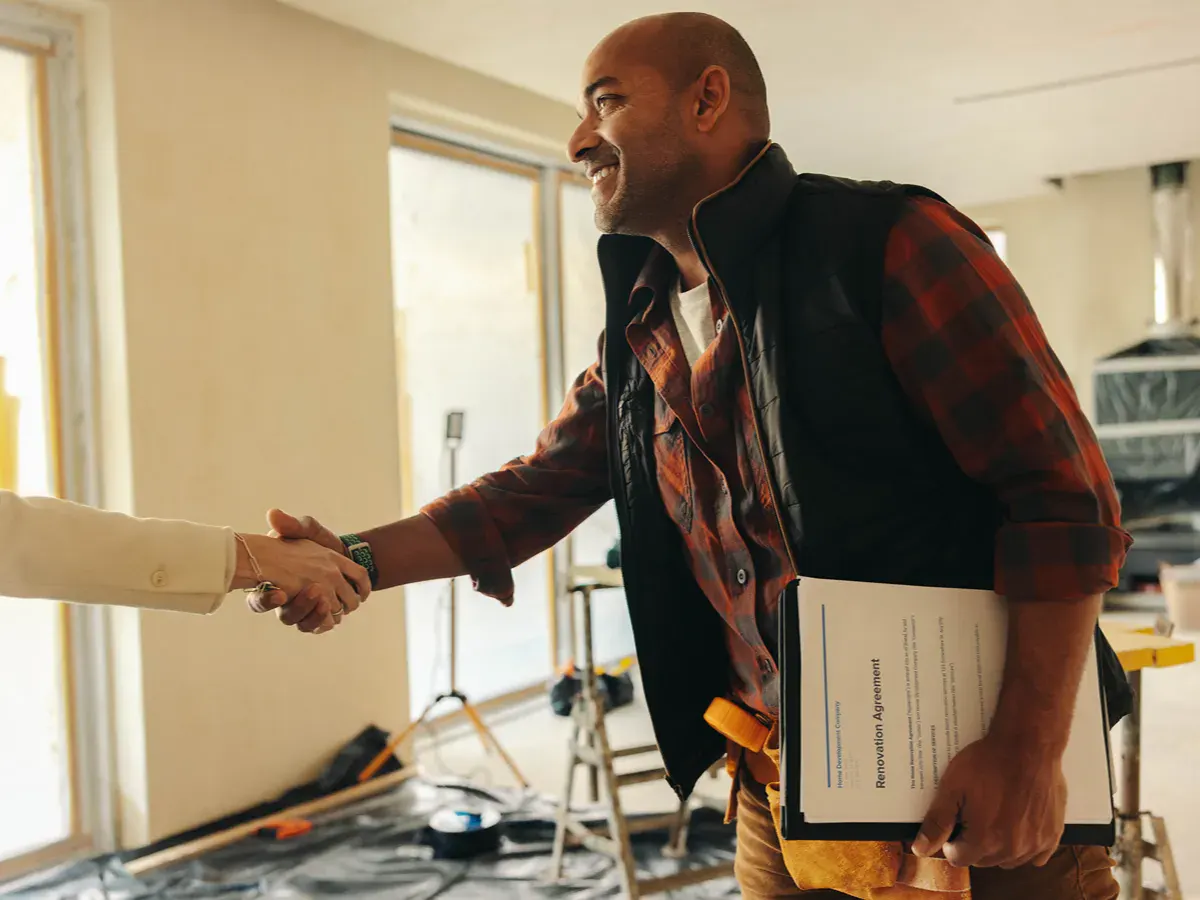 A person holding a clipboard and shaking another person's hand.