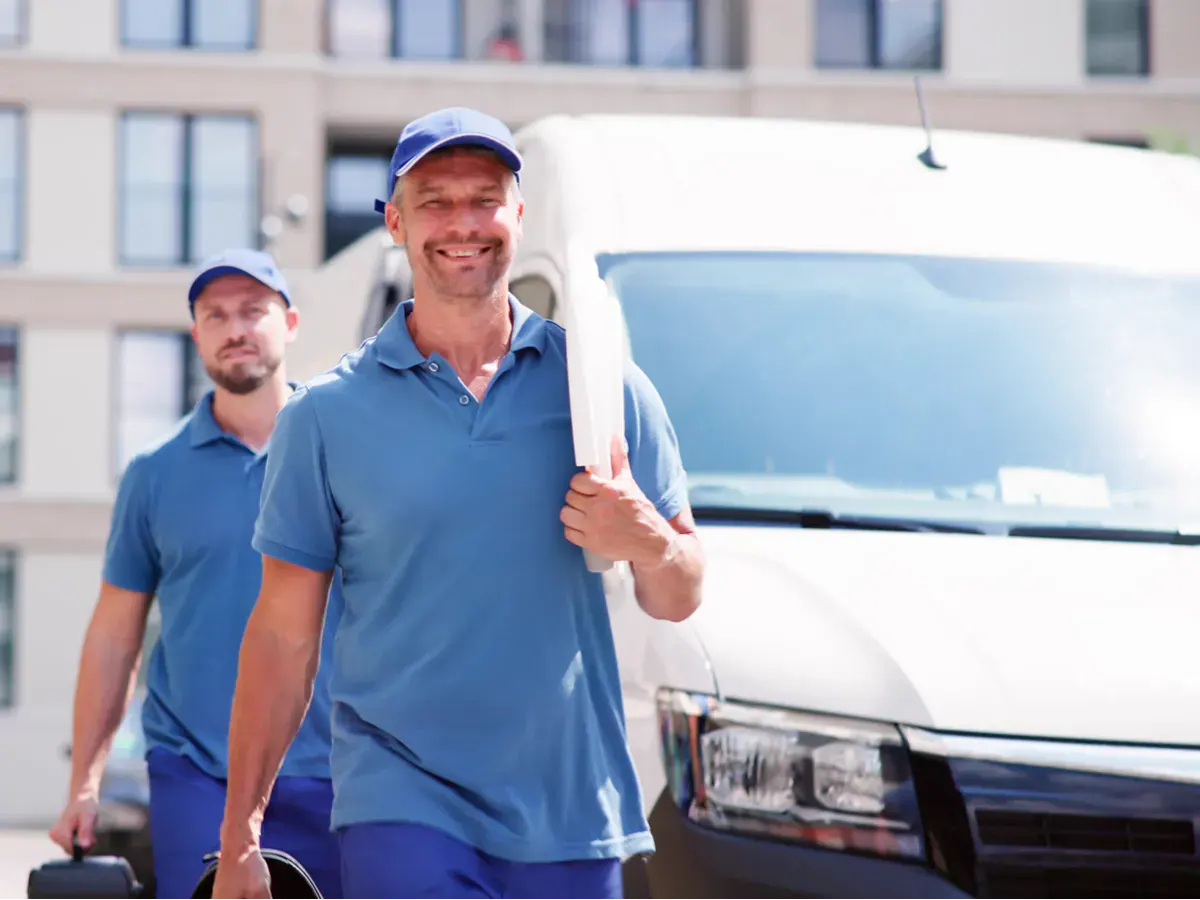 Two people wearing blue shirts and standing near a vehicle.